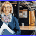 A professional woman holding notebooks in a modern office environment, representing marketing automation strategy for a Polish publishing house.